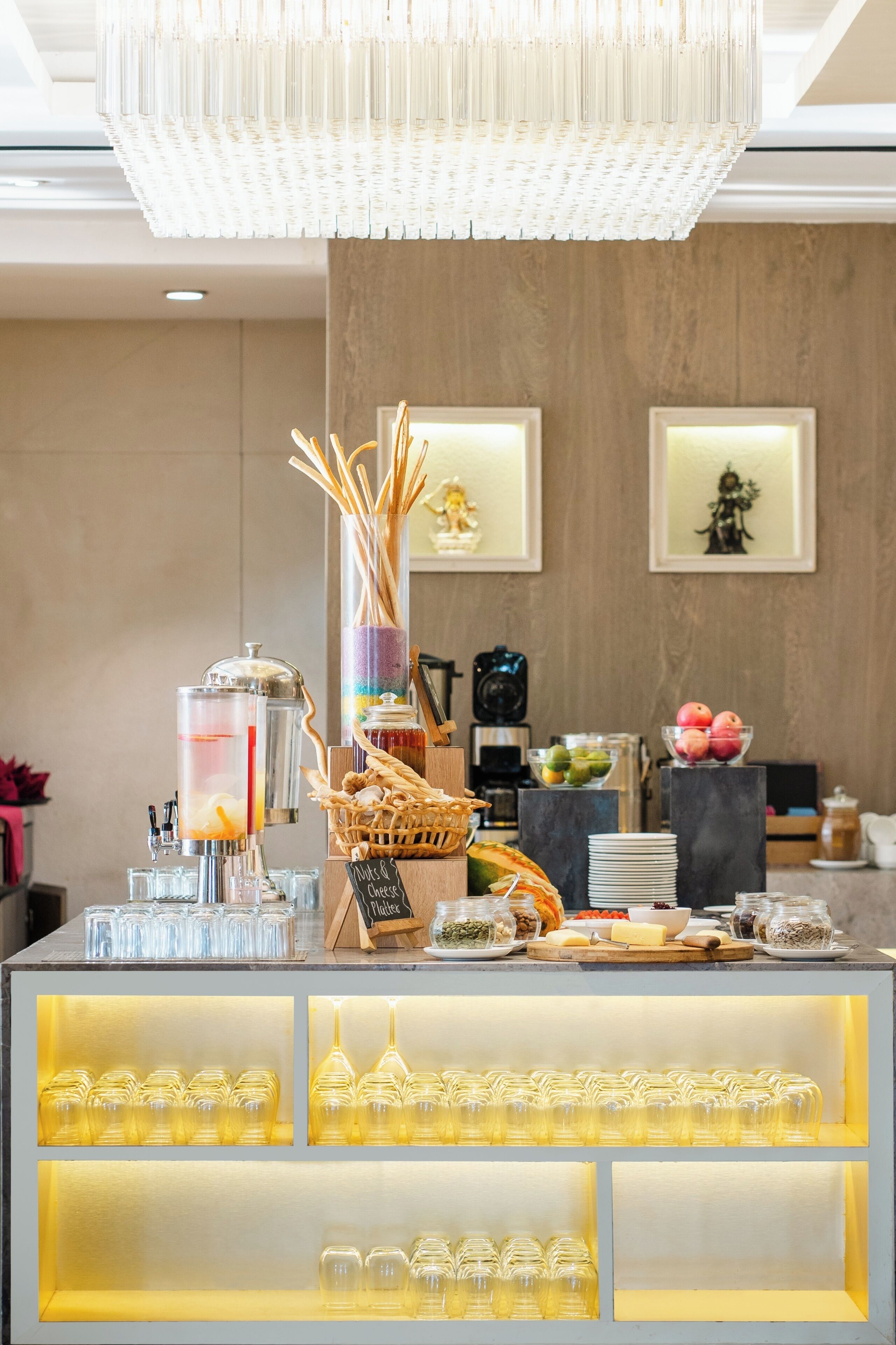Disposição de buffet com diversos alimentos, uma máquina de café e um lustre decorativo.