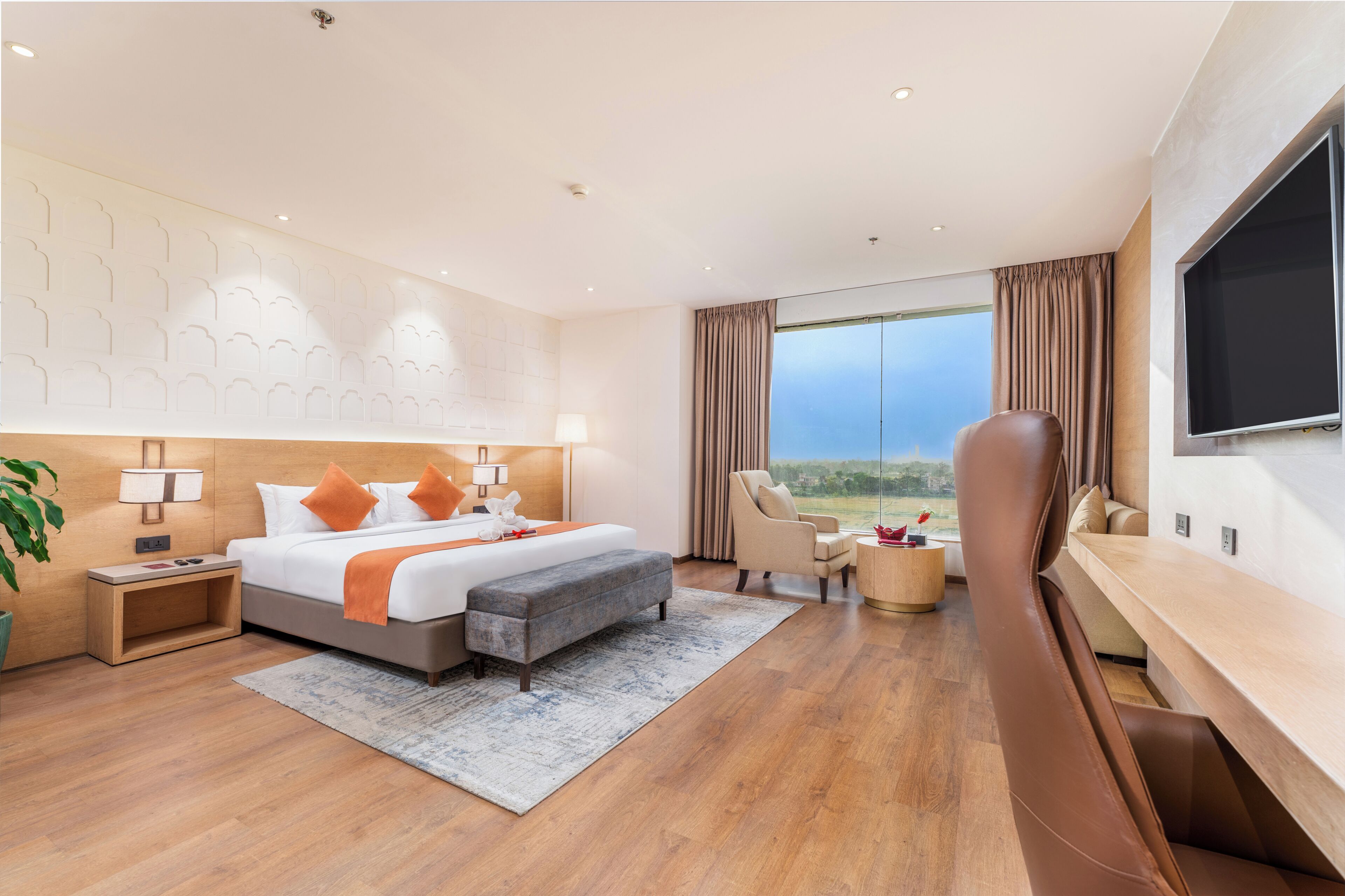 Habitació d'hotel moderna amb un llit gran, una taula de treball, una cadira i una televisió.