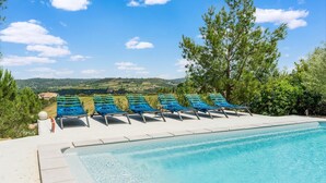 Zona de piscina con sillones de descanso y vistas al campo.