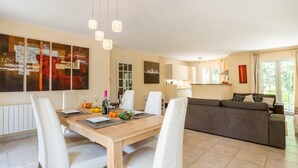 Una sala moderna con comedor, un sofá y una cocina al fondo.