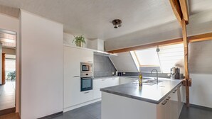 A modern kitchen with white cabinetry, a central island, and a skylight. - Cottage on sheep farm with gelateria (Merksplas)