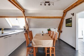A dining area with a table set for six, wooden chairs, a white tablecloth, and a potted plant. - Cottage on sheep farm with gelateria (Merksplas)