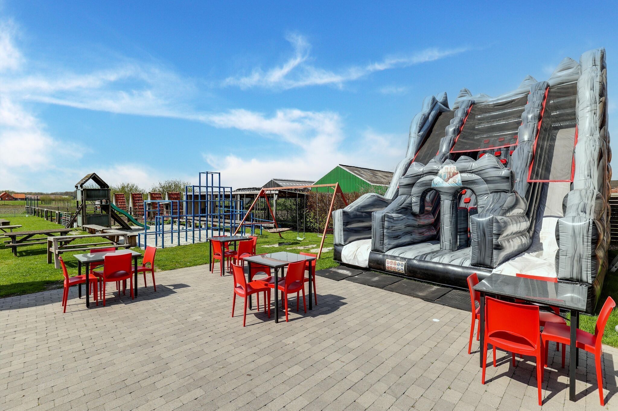 A playground with slides and climbing structures, picnic tables, and a large inflatable slide.