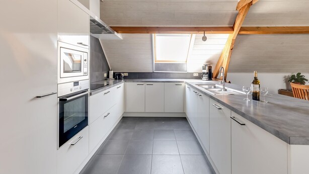 A modern kitchen with white cabinets, a built-in oven, and a large window providing natural light. - Cottage on sheep farm with gelateria (Merksplas)