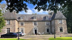 A stone building with a symmetrical facade, multiple windows, and a central entrance.