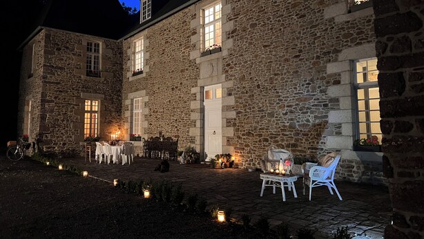 A stone building with a courtyard, outdoor seating, and candles.