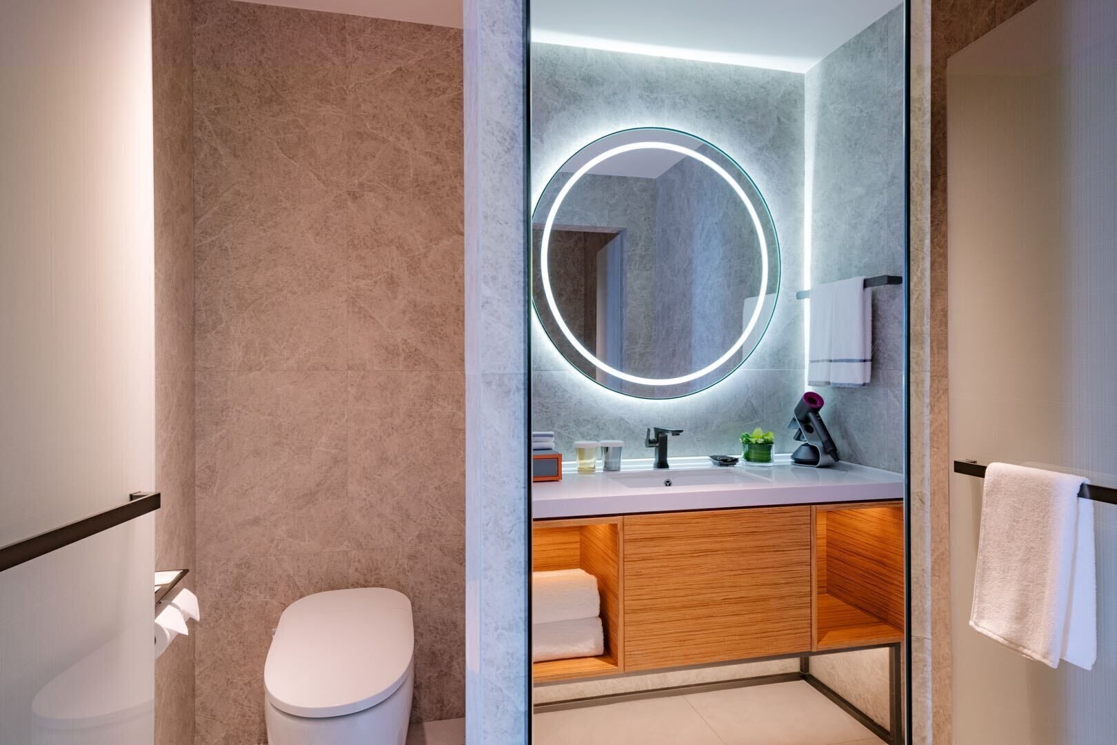 A modern bathroom with a toilet, a vanity with a mirror, and a towel rack.