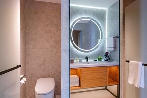 Un baño moderno con inodoro, tocador con espejo y toallero.