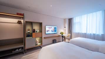 Una habitación de hotel moderna con una cama grande, una zona de estar con televisor y una mesita con un jarrón de flores.