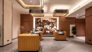 Un vestíbulo moderno con mostradores de recepción de madera, un diseño geométrico en la pared y lámparas contemporáneas.