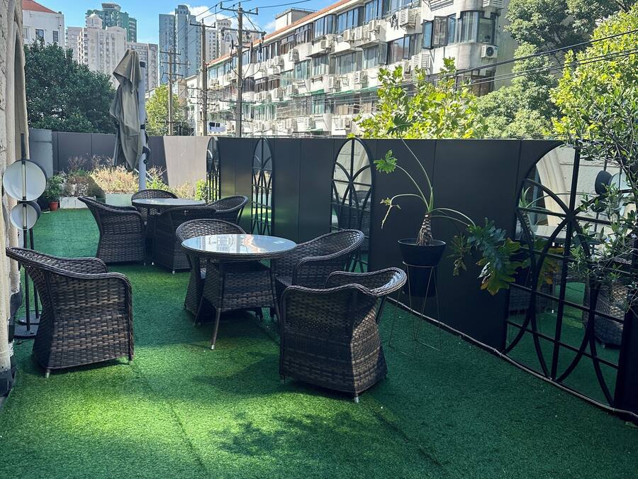 Un patio al aire libre con césped artificial, mobiliario de mimbre y plantas en macetas.