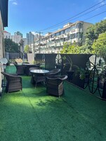 An outdoor patio with artificial grass, wicker furniture, and potted plants.