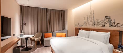 A hotel room with a bed, a desk, a chair, a small table, a TV, and a wall mural.