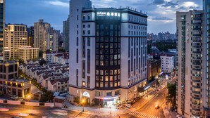 Un hotel de varios pisos con una ubicación destacada en una esquina, que cuenta con una entrada amplia y un letrero de restaurante visible.