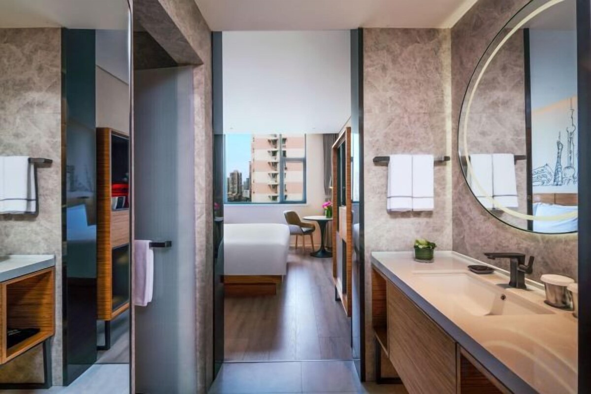Un baño moderno con tocador, espejo y vistas a la ciudad.