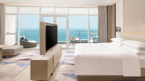 A modern hotel room with a large bed, a flat-screen TV, and a balcony with a view of the sea. - Sheraton Beihai Resort (Beihai)
