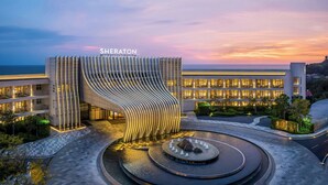 A modern hotel with a unique curved facade and a well-lit entrance. - Sheraton Beihai Resort (Beihai)