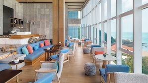 A spacious lounge area with a large seating area, a bar, and large windows offering a view of the ocean. - Sheraton Beihai Resort (Beihai)