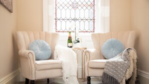 A two-seater sofa with decorative pillows and a blanket, positioned in front of a window with a decorative grille. - Redmayne House in Kirkby Stephen (Kirkby Stephen)