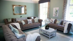 A living room with two sofas, a coffee table, a mirror, and artwork on the walls. - Redmayne House in Kirkby Stephen (Kirkby Stephen)