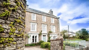 A stone building with white shutters, a gravel driveway, and a metal fence. - Redmayne House in Kirkby Stephen (Kirkby Stephen)