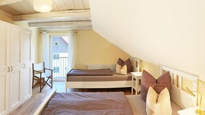 A bedroom with two beds, a chair, and a view of the outside.
