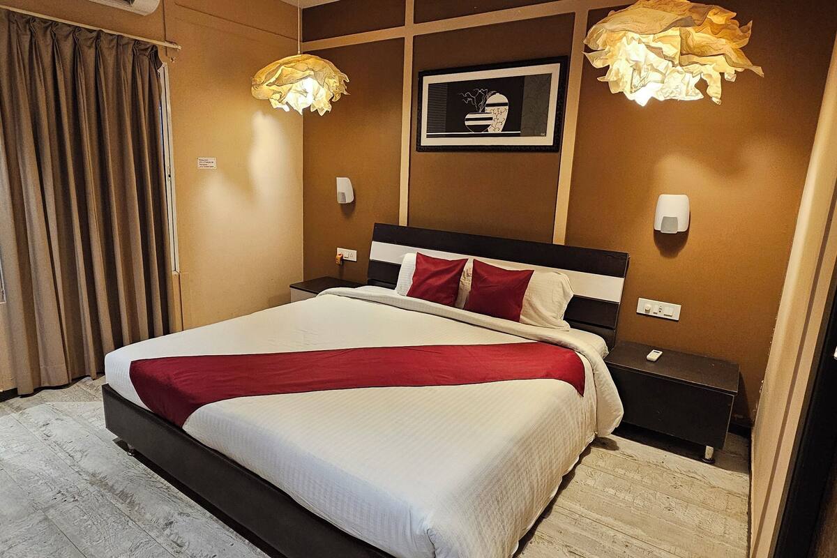 A hotel room with a large bed, two bedside tables, a bedside lamp, a mirror, and a framed picture on the wall.