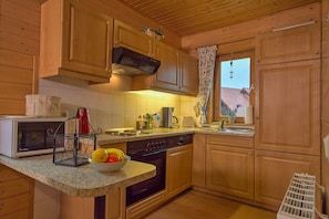 A kitchen with wooden cabinets, a microwave, a stove, and a sink.