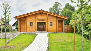 Uma cabana de madeira com entrada pavimentada, uma placa indicando que é uma casa de sauna, e o número '5a' na porta.