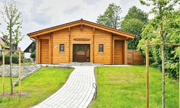 A wooden cabin with a paved entrance, a sign indicating it is a sauna house, and a number '5a' on the door.