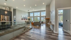 A spacious living area with a glass railing, a dining area, and a kitchen with modern appliances. - Fairmont Peak Cabin | Pet Friendly | Pool Table (Area F (Columbia Lake/Windermere Lake))