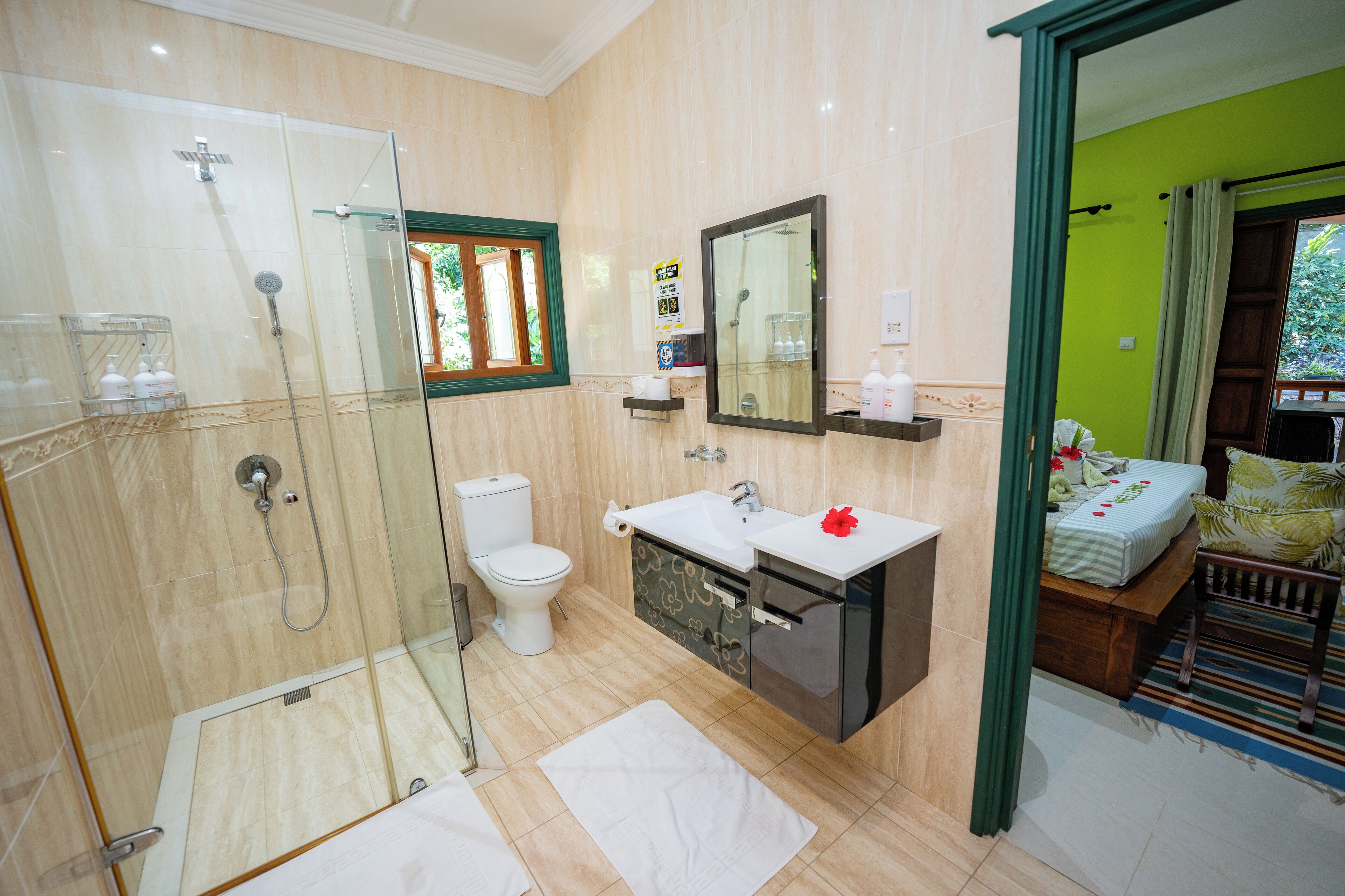 A bathroom with a glass-enclosed shower, a toilet, a sink, and a mirror.