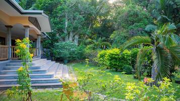 A lush garden with a staircase leading to a covered porch.