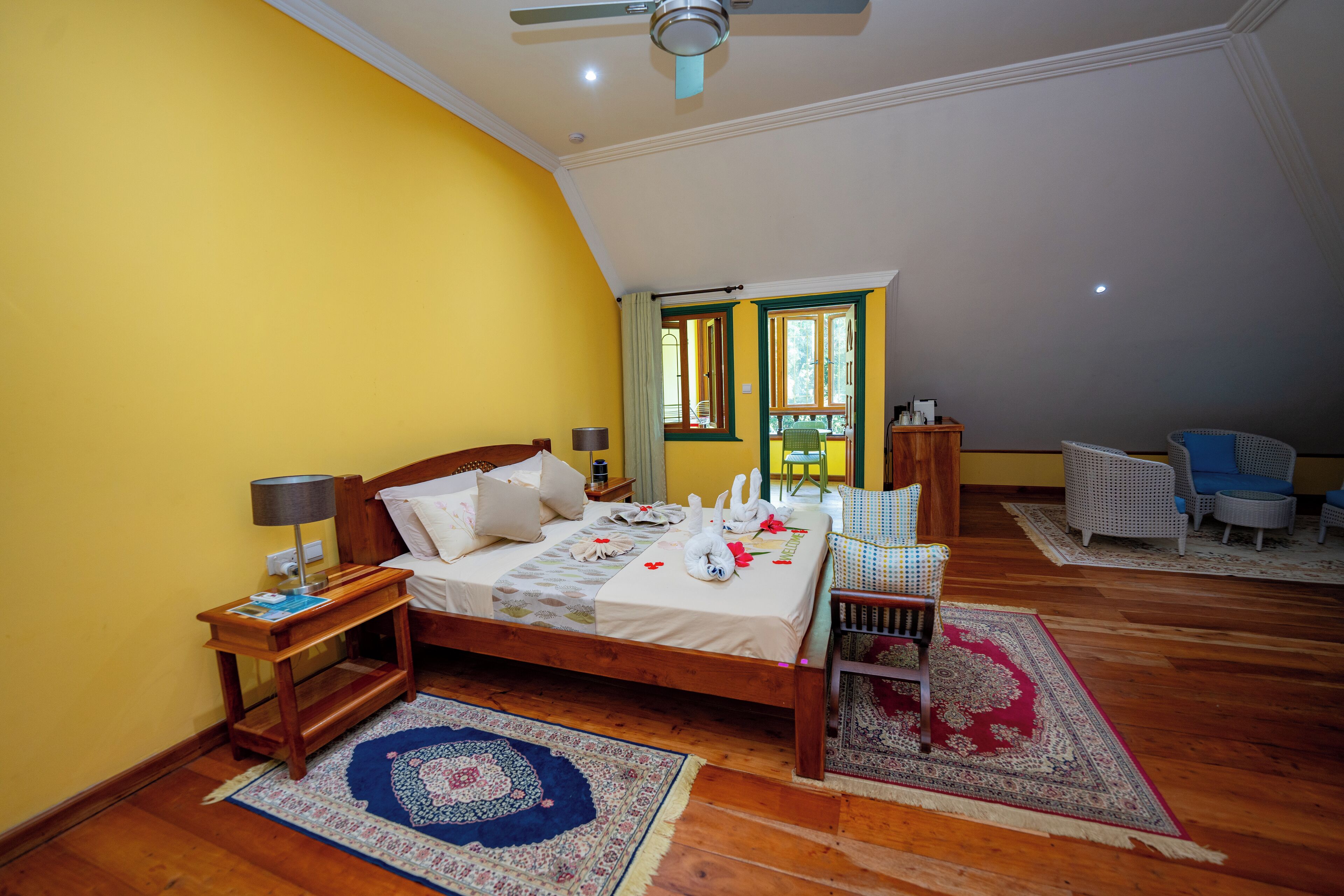 Un dormitorio con una cama de madera, una mesita de noche, una silla, una pequeña mesa y una ventana con vistas.
