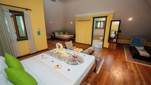 Habitación de hotel con una cama bien hecha, una zona de estar con una silla, una mesita y un espejo.