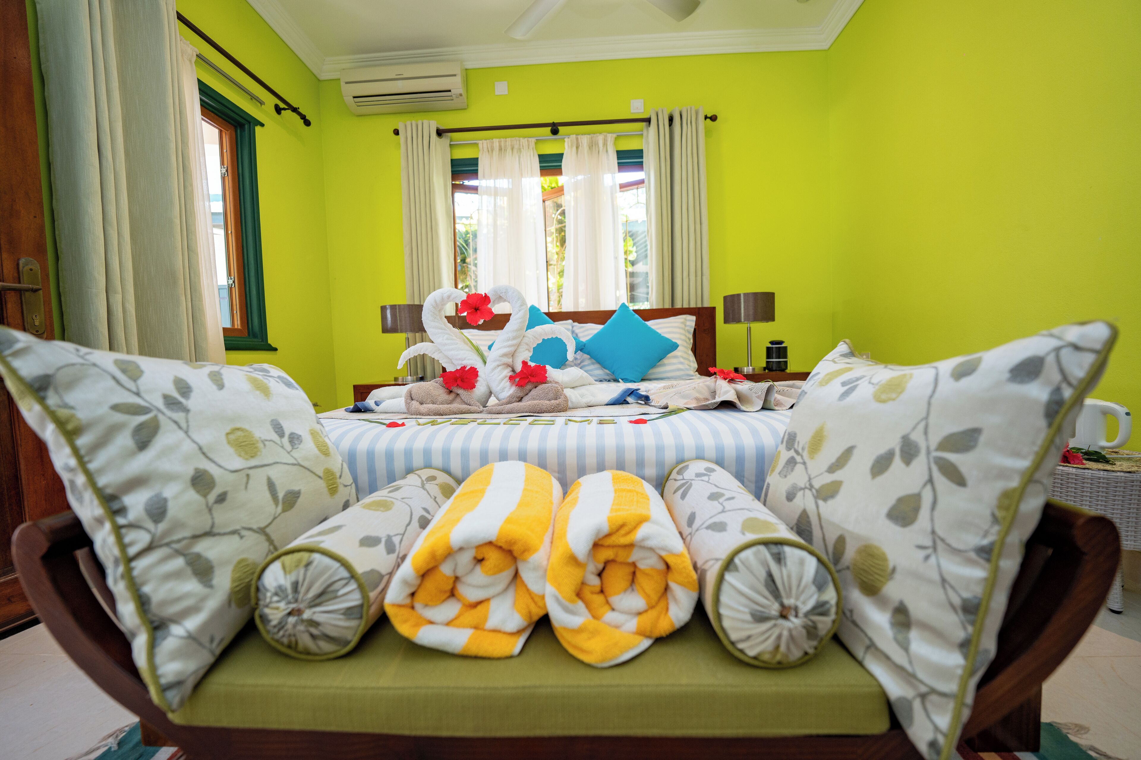 A bright green room with a bed, pillows, and a window with curtains.