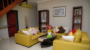 Una sala de estar con dos sofás amarillos, una mesa de centro y una estantería.