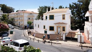 Un edificio bianco con tetto in tegole, muro in pietra e cancello nero.