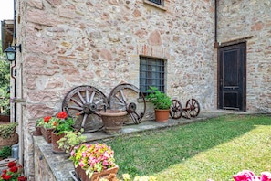 A stone building with a door, windows, and a row of old wheels.