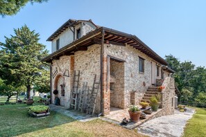 A stone building with a wooden staircase, a small porch, and potted plants.