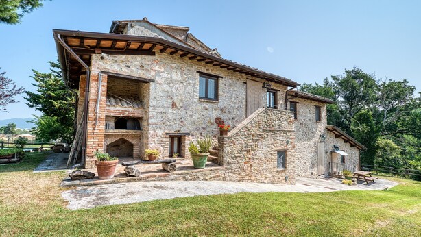 A stone building with a fireplace, outdoor seating, and a staircase leading to the entrance. - Farmhouse 'Casale Storico Xvii Sec - Tulipano' with Mountain View and Shared Pool (Giano dell'Umbria)