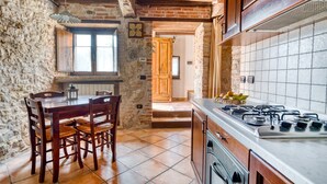 A rustic kitchen with exposed brick walls, a wooden dining table with chairs, a gas stove, and a tiled backsplash. - Holiday Home 'Casale Storico XVII Sec - Rosa' with Mountain View, Shared Pool and Wi-Fi (Giano dell'Umbria)