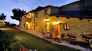 A stone building with a covered patio, outdoor seating, and a well-maintained lawn. - Holiday Home 'Casale Storico XVII Sec - Rosa' with Mountain View, Shared Pool and Wi-Fi (Giano dell'Umbria)