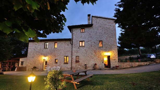 A stone building with multiple windows, a wooden bench, and a small tree in the foreground. - Holiday Home 'Casale Storico XVII Sec - Rosa' with Mountain View, Shared Pool and Wi-Fi (Giano dell'Umbria)
