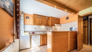 Une cuisine avec des meubles en bois, un lave-vaisselle, un four à micro-ondes et un dosseret carrelé.