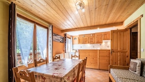 Un intérieur en bois comprenant une table à manger, des chaises, un canapé et un coin cuisine.