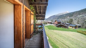 Un balcon en bois offrant une vue sur une montagne et des maisons.