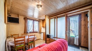 Een houten interieur met een eethoek, kitchenette en een rode bank.