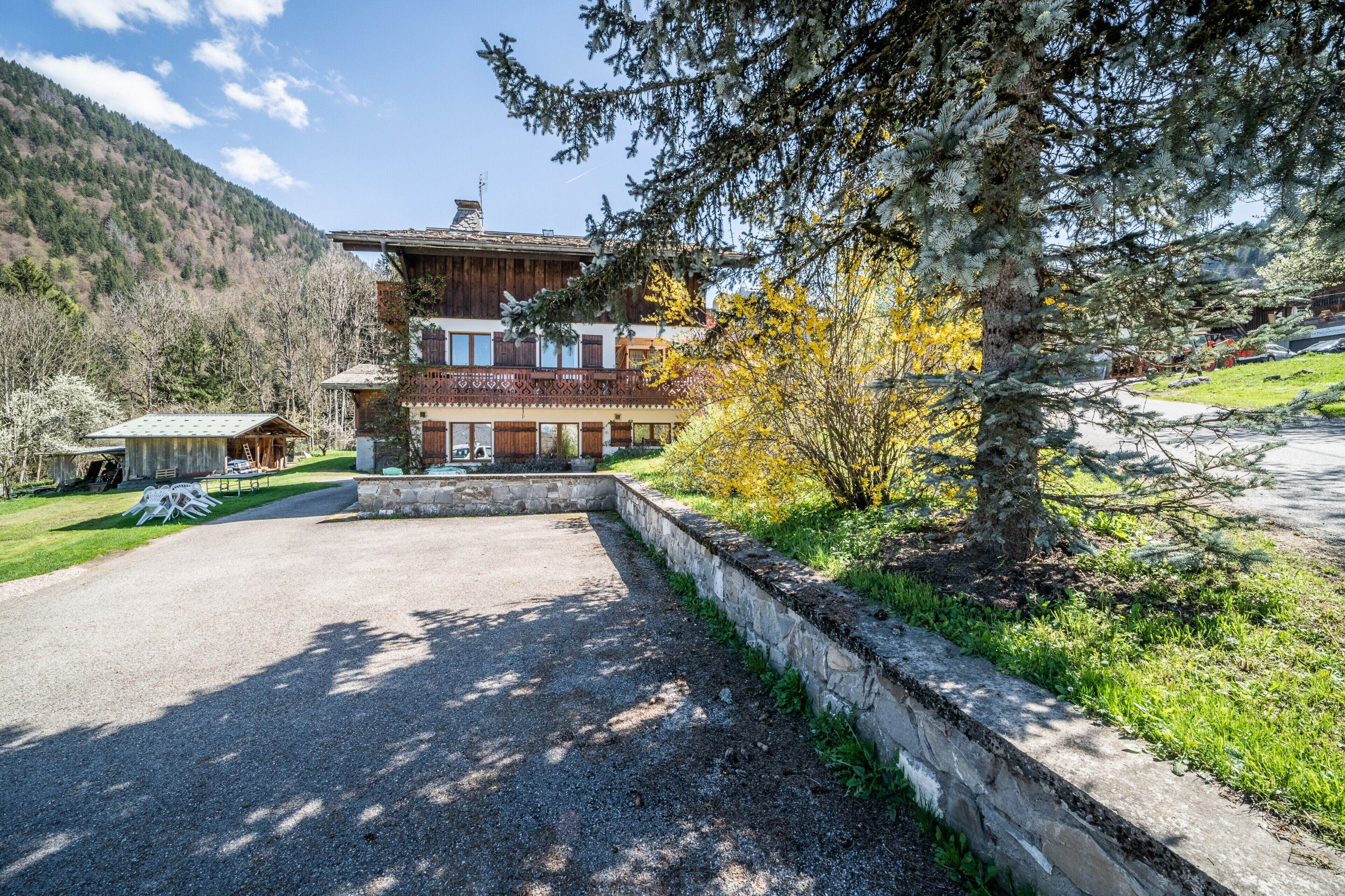 Un bâtiment à deux étages, doté de fondations en pierre, d’une allée pavée et d’un espace verdoyant avec des arbres.