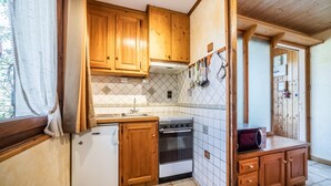 Een kleine keuken met houten kastjes, een koelkast, een oven en een magnetron.
